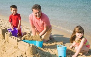 24805826...Grandfather and grandchildren making sandcastle